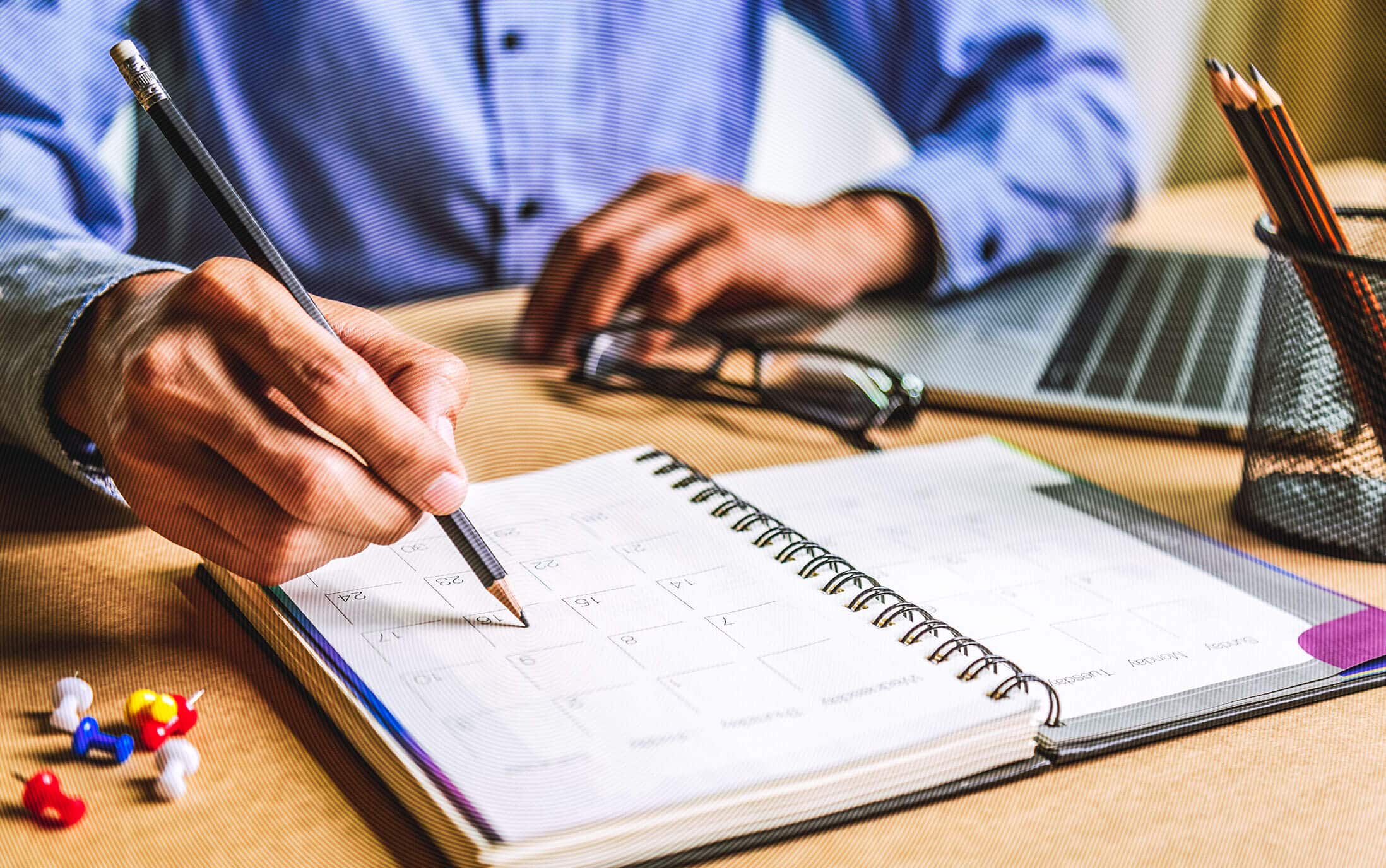 Person notiert mit Bleistift im Kalender