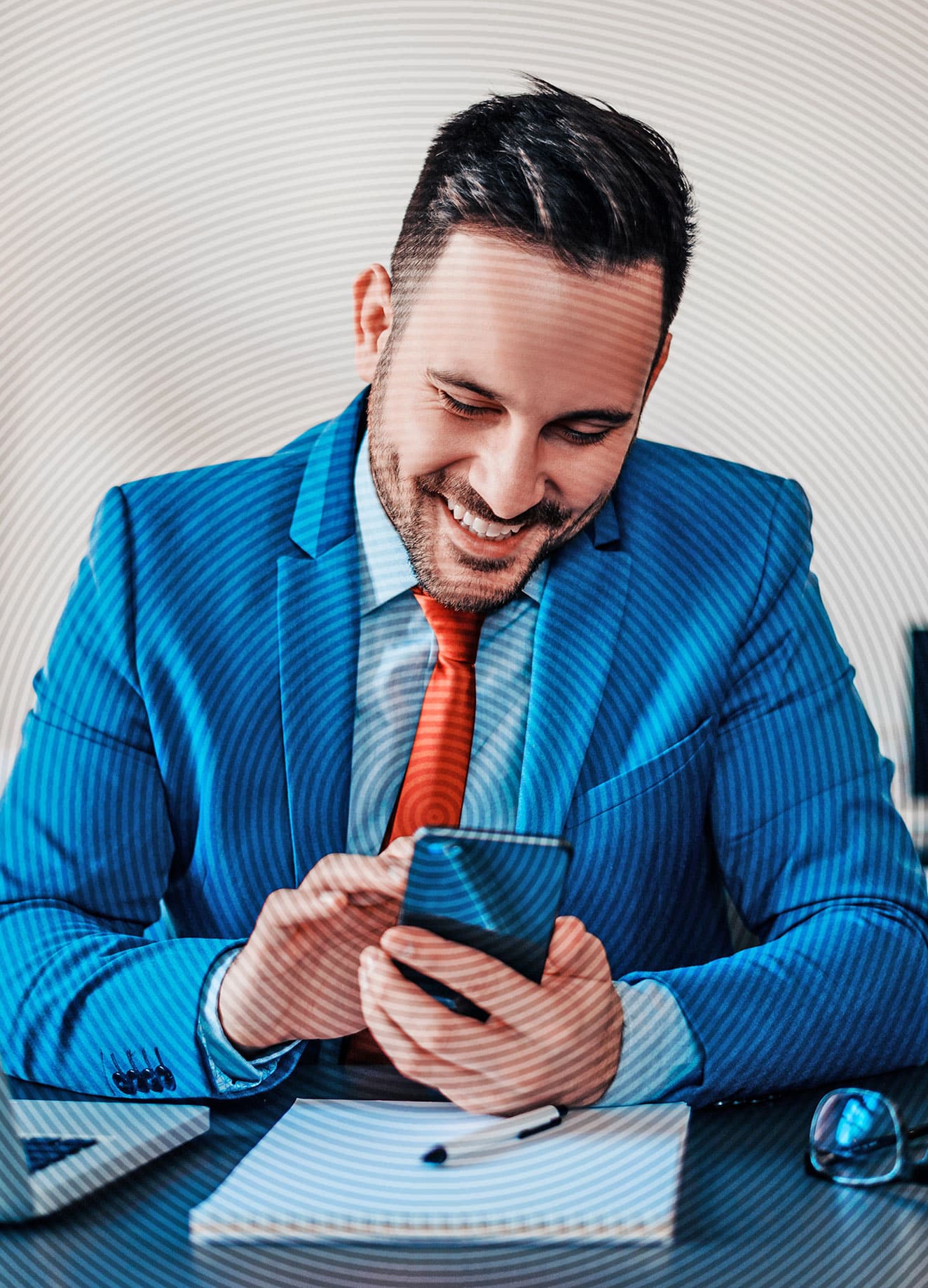 Fröhlicher Geschäftsmann im hellblauen Anzug und roter Krawatte tippt auf dem Smartphone