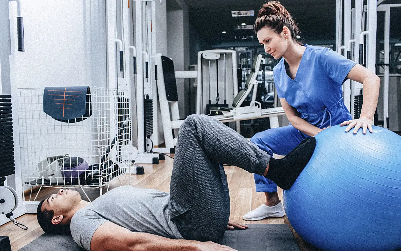 Physiotherapeutin betreut Patienten bei einer Übung mit Gymnastikball